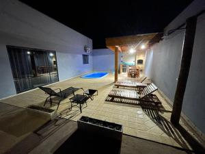 um pátio com cadeiras e uma piscina à noite em Cantinho Estrelado - Casa automatizada com ALEXA em Brotas