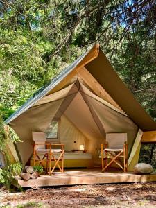 une tente avec deux chaises et un lit. dans l'établissement Glamping Tent Water Village Rogla, à Oplotnica