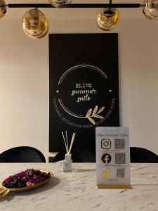 une table avec un bol de fleurs violettes et un panneau dans l'établissement Elite Summer Suite, à Năvodari