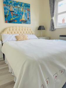a bedroom with a large white bed with a painting on the wall at Serenity Station in Hornsea