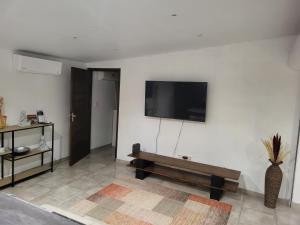 sala de estar con TV en una pared blanca en Résidence Ariane en Bourda