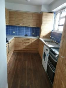 cocina con armarios de madera y lavadora en Rowland Hill House, en Londres