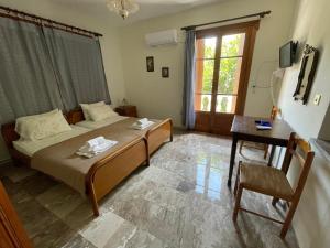 a bedroom with a bed and a table and a window at Villa Apostolis Studios in Skopelos Town