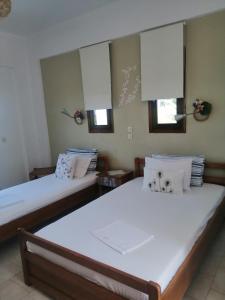 two beds in a room with two windows at Avra Ηouse in Kriopigi