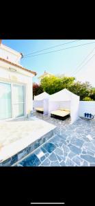 un patio con 2 bancos blancos y una casa en Exclusive Villa Larnaca - 8 plus sleeps - 2 min from BEACH - Big Private Pool, en Pyla
