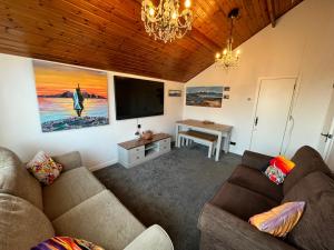 uma sala de estar com 2 sofás e uma televisão de ecrã plano em The Mail Barn Studio em Lamlash