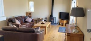 a living room with a leather couch and a tv at Adorable 1 bed log cabin with log burner in Frome