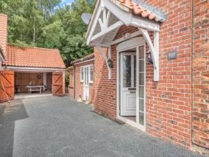 a brick house with a white door and a patio at Dovedale Cottage in Coningsby