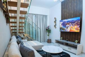Blackforest 2BR Duplex at Masdar Oasis في أبوظبي: غرفة معيشة مع أريكة وتلفزيون