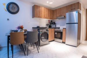 a kitchen with a refrigerator and a table with chairs at Darkwood Haven - Luxe 2BR Duplex Stay in Oasis, Near Masdar City in Abu Dhabi