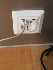 a white electrical outlet with a cord plugged into it at Cottage, boat, spa, private dock, Lillesand in Lillesand