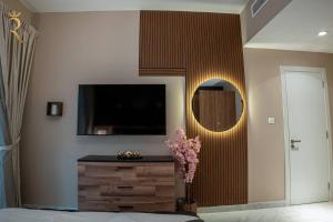 a bedroom with a television and a dresser with a flower at Darkwood Haven - Luxe 2BR Duplex Stay in Oasis, Near Masdar City in Abu Dhabi