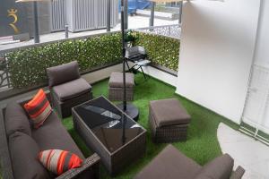 a balcony with a couch and a table and chairs at Darkwood Haven - Luxe 2BR Duplex Stay in Oasis, Near Masdar City in Abu Dhabi