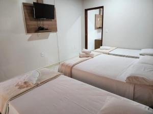 a room with three beds and a flat screen tv at Pousada Casa Rosa in Alto Paraíso de Goiás