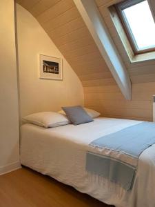ein Schlafzimmer mit einem Bett im Dachgeschoss mit einem Fenster in der Unterkunft Joli appartement au cœur du village in Saint-Briac-sur-Mer