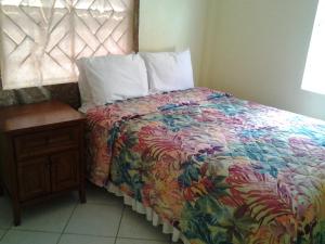a bedroom with a bed with a colorful comforter and a table at Aupic Paradise in Vieux Fort