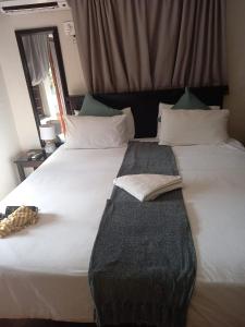un grande letto bianco con due asciugamani sopra di The Success Guest House a Standerton