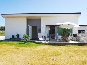 a white house with a patio with an umbrella at Modern Beach Cottage in Tofta, Gotland in Gnisvärd
