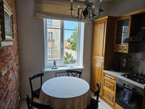 a kitchen with a table with chairs and a window at Kalnelio Apartment in Klaipėda