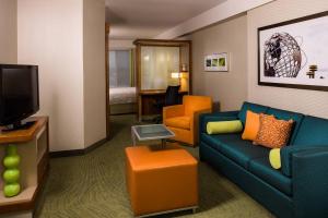 um quarto de hotel com um sofá e uma televisão em SpringHill Suites by Marriott New York LaGuardia Airport em Queens