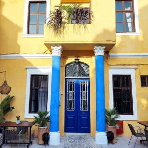 żółty budynek z niebieskimi kolumnami i niebieskimi drzwiami w obiekcie Rhodes Youth Hostel w mieście Rodos