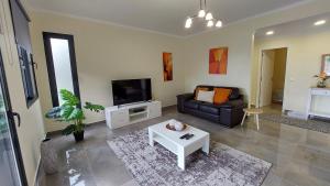 een woonkamer met een bank en een tv bij Villa Strelitzia in Funchal