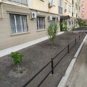 una valla frente a un edificio con dos árboles en Leo, en Atyraū