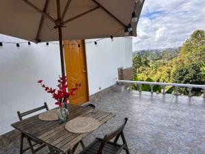 una mesa de madera con sillas y una sombrilla en el balcón en Cabañas con jacuzzi y chimenea - Casa Floral, Marinilla, en Marinilla