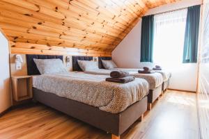 two beds in a bedroom with a wooden ceiling at Domki Ania in Łeba