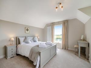 a white bedroom with a bed and a window at Manor Farm Cottage in Hornby