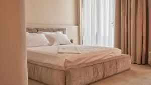 a bed in a bedroom with a large window at Azar Luxury Suites in Vlorë