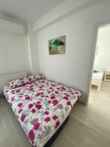 バイレ・フェリクスにあるApartament Oanaのベッドルーム1室(花柄のベッドカバー付) +1枚の写真