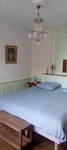 1 cama grande en un dormitorio con lámpara de araña en les chambres fleuries, en Saint-Benoît-du-Sault