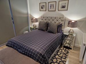 a bedroom with a bed with a checkered blanket and two lamps at leigh Penthouse Apartment in Leigh-on-Sea