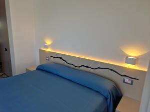 a bedroom with a blue bed with two lights on it at Hotel Da Maria in Ischia