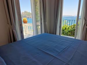 a bedroom with a blue bed and a large window at Hotel Da Maria in Ischia