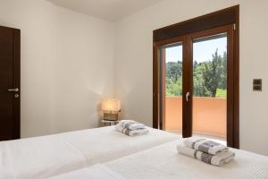 two beds in a bedroom with two towels on them at Glamorous Villa Nefeli in Koskinou