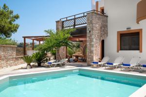 a swimming pool with chairs and a house at Glamorous Villa Nefeli in Koskinou