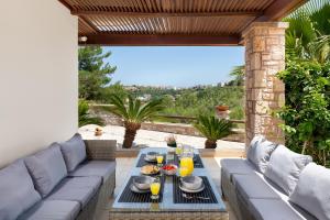 a patio with a couch and a table with drinks at Glamorous Villa Nefeli in Koskinou