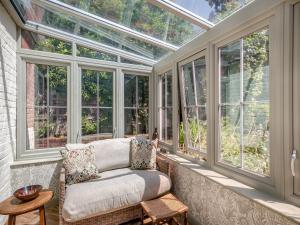 a conservatory with a couch in a room with windows at The Old Reading Room in Salhouse