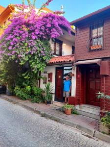 イスタンブールにあるVilla Sphendone Suites Istanbulの紫の花の家の戸に立つ男