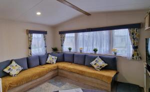 ein blaues Sofa im Wohnzimmer mit Fenstern in der Unterkunft Cwtch, White Horse, Seal Bay Resort in Selsey