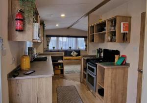 cocina con armarios de madera y sala de estar. en Cwtch, White Horse, Seal Bay Resort, en Selsey