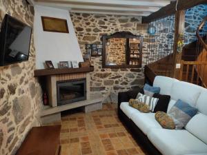 ein Wohnzimmer mit einem Sofa und einem Kamin in der Unterkunft Casa rural de piedra en una aldea tranquila de Zas 