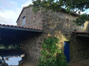 Casa rural de piedra en una aldea tranquila de Zas : سيارة متوقفة أمام مبنى من الطوب