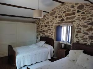 Casa rural de piedra en una aldea tranquila de Zas : غرفة نوم بسريرين وجدار حجري