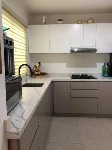 a kitchen with white cabinets and a sink and a stove at Casa “PLAYA DORADA” in Mazatlán