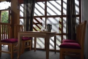 a table and two chairs in front of a window at Siwakhat Huts in Shoghot