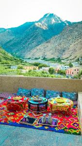 un tavolo con sedie su un tappeto con montagne sullo sfondo di Toubkal home stay a Imlil