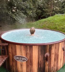 a person in a pool of water in a wooden tub at Chata Ignasia pod Śnieżnikiem 1 na działce in Stronie Śląskie